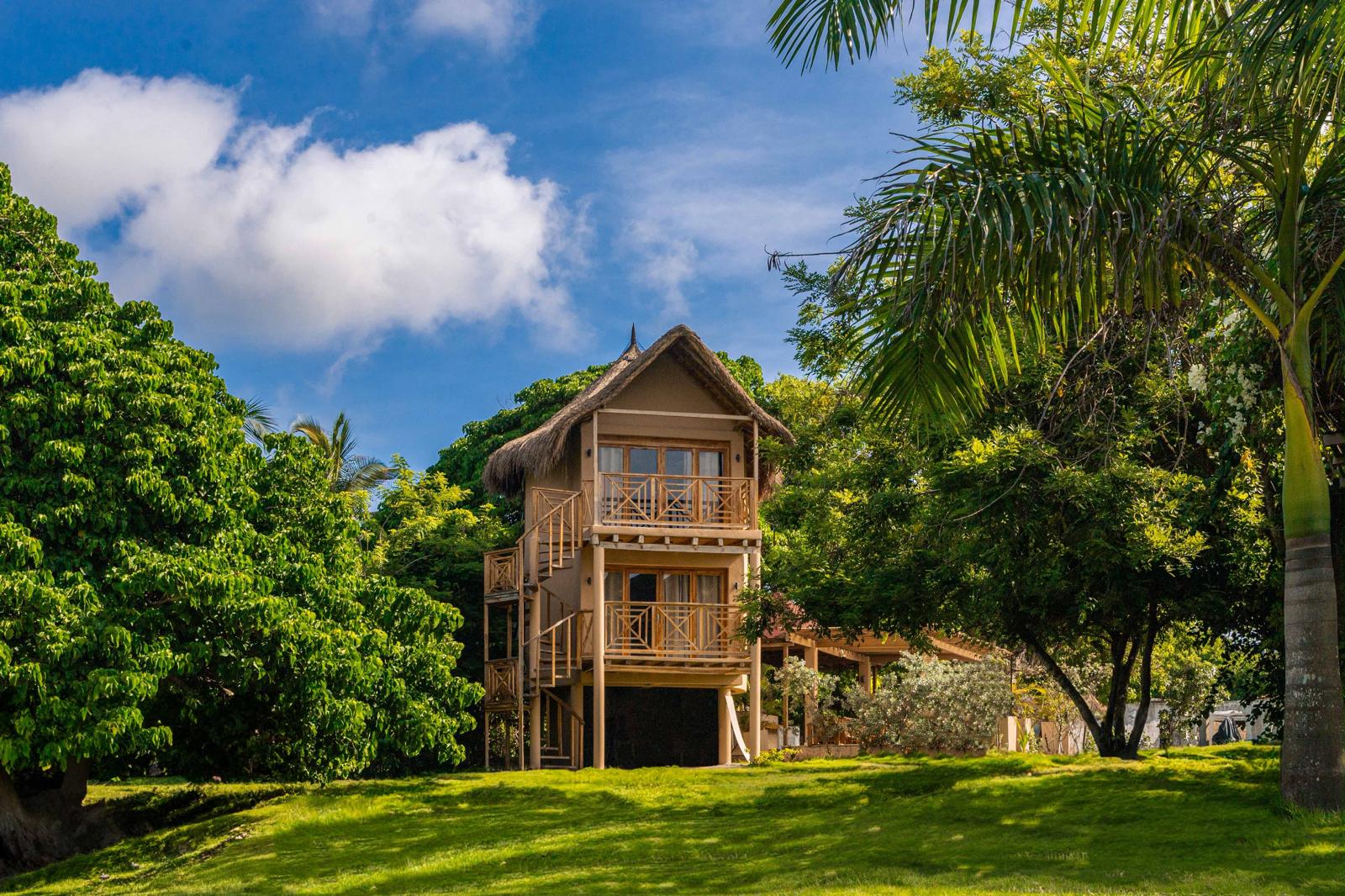 Two-storey thatched bungalow set in tropical gardens