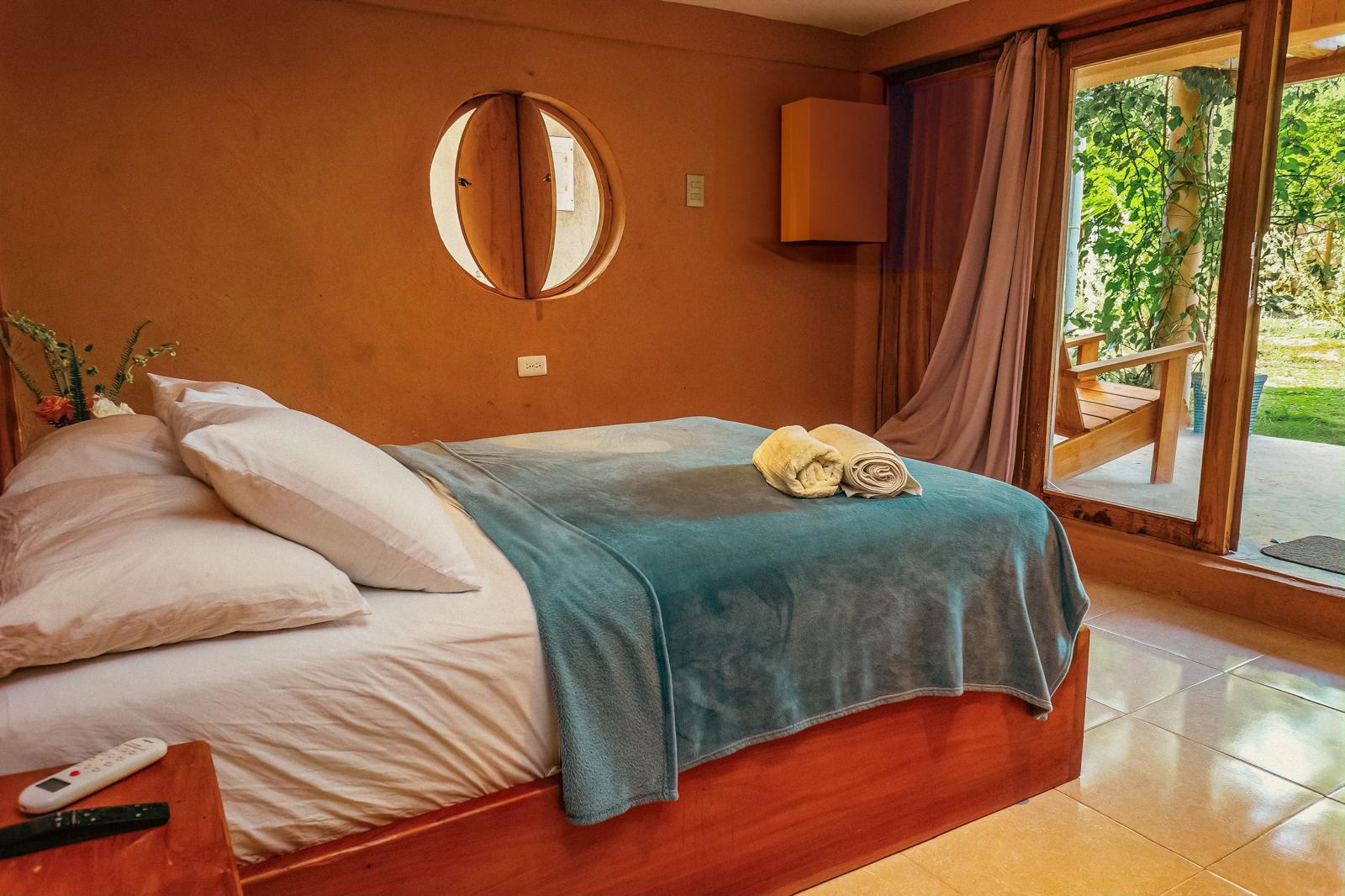 Terracotta bedroom with round teak window and garden terrace